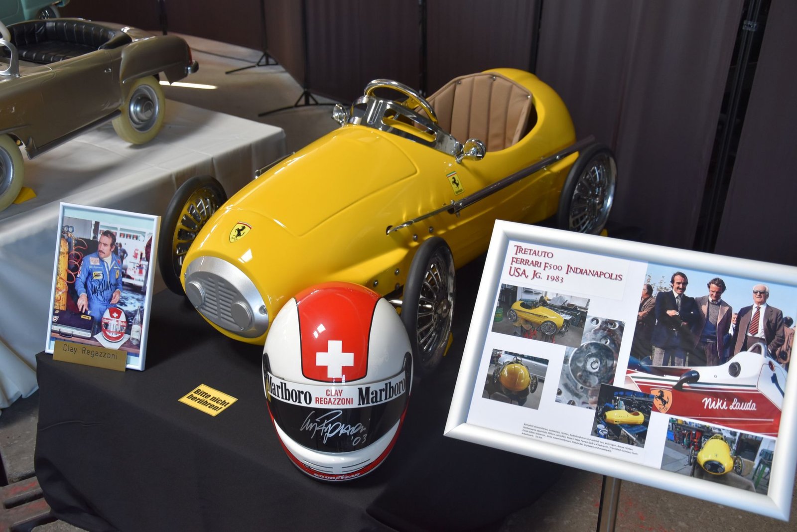 Ein Helm mit einem Schweizer Kreuz darauf sitzt neben einem gelben Spielzeugauto